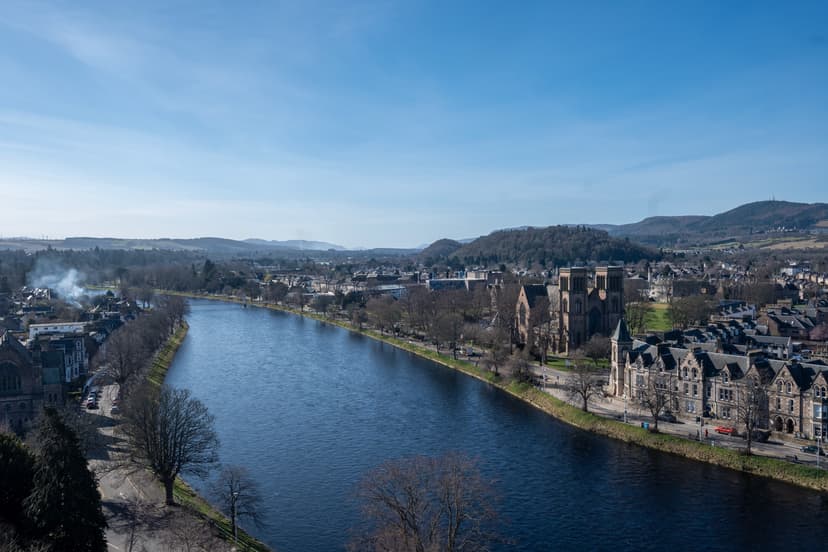River Ness flowing through Inverness with historic buildings and cathedral under a clear blue sky