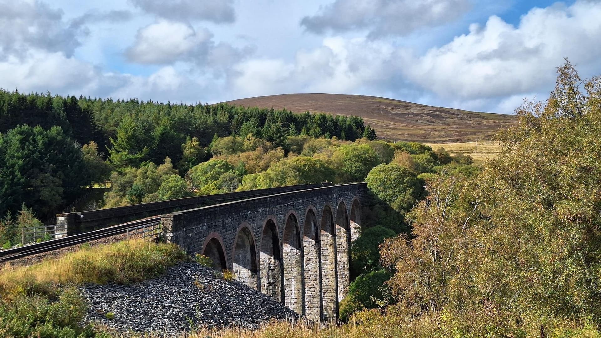 Stone railway viaduct crossing valley near Inverness towards Cairngorm mountains.