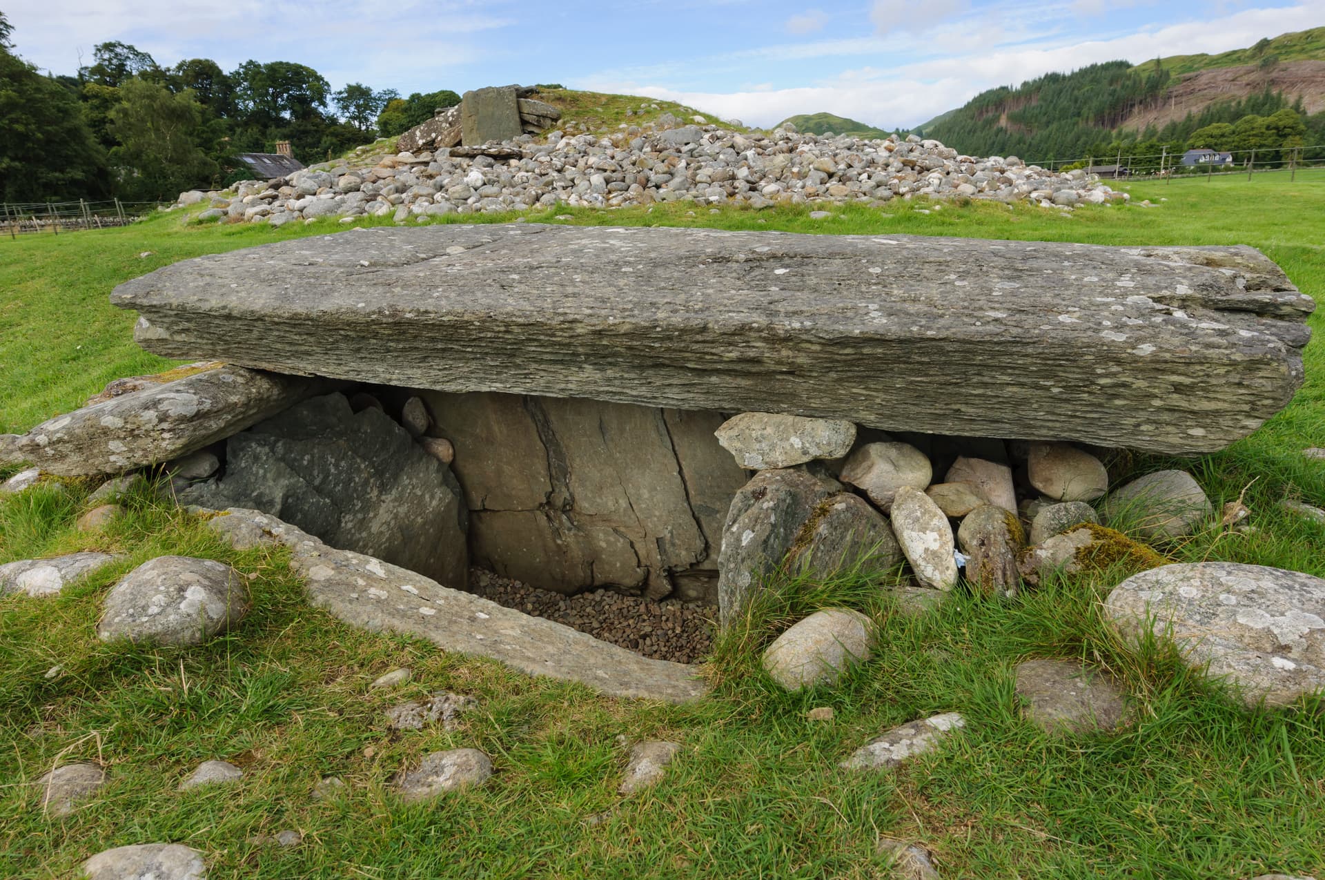 Burial chamber with large capstone and surrounding stones in grassy field at Kilmartin Glen.