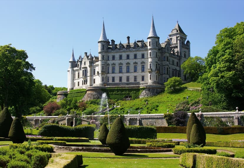 Dunrobin Castle with formal gardens and fountain under blue sky