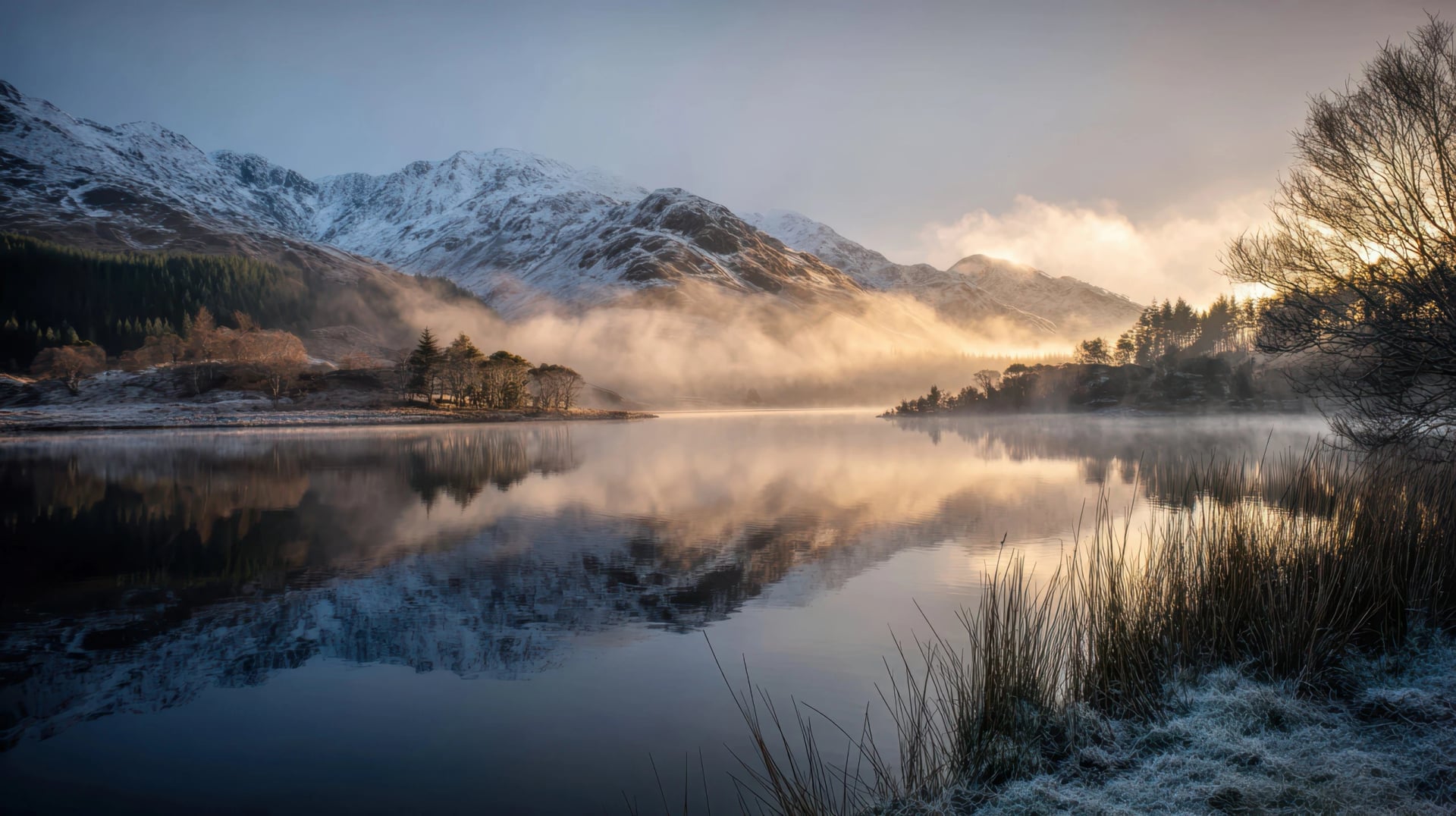 Calm winter morning at the lake with mist, mountains, and reflections in the water in the Scottish Highlands